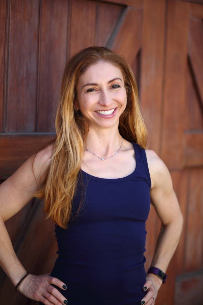 A woman standing in front of a wooden wall.