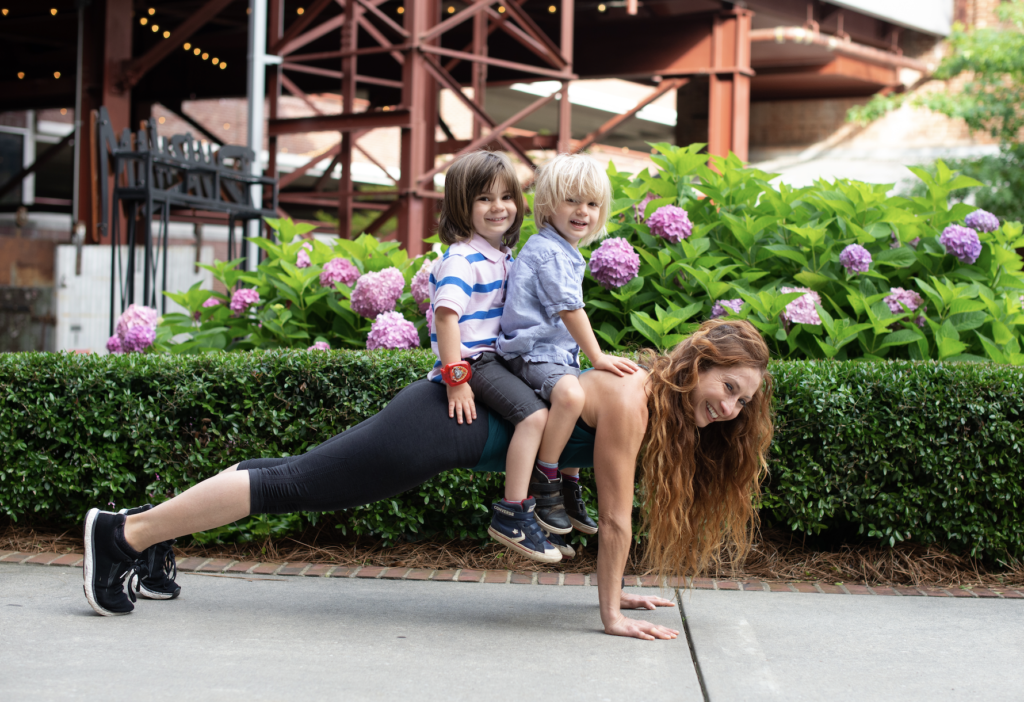 A woman is doing yoga with two kids.